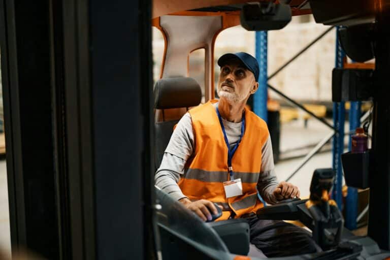 Conducteur opérant un chariot élévateur dans un entrepôt.