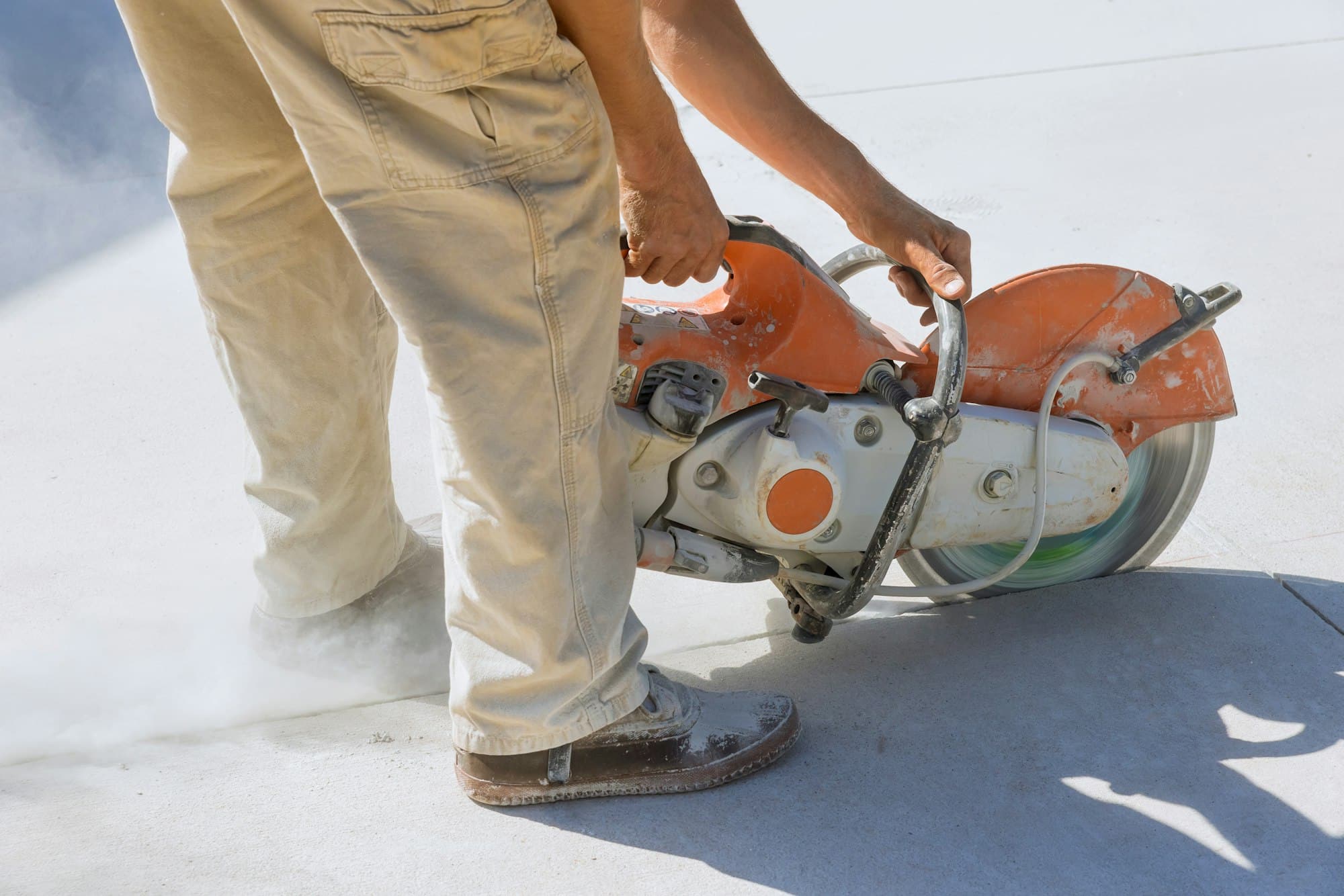 Ouvrier utilisant une scie circulaire sur un chantier pour découper du béton